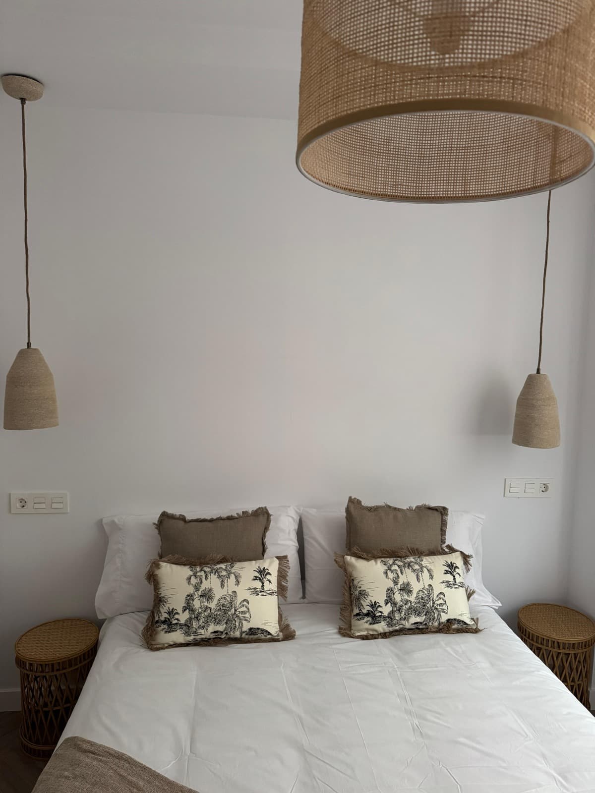 Dormitorio con cojines tropicales y mesitas de bambú